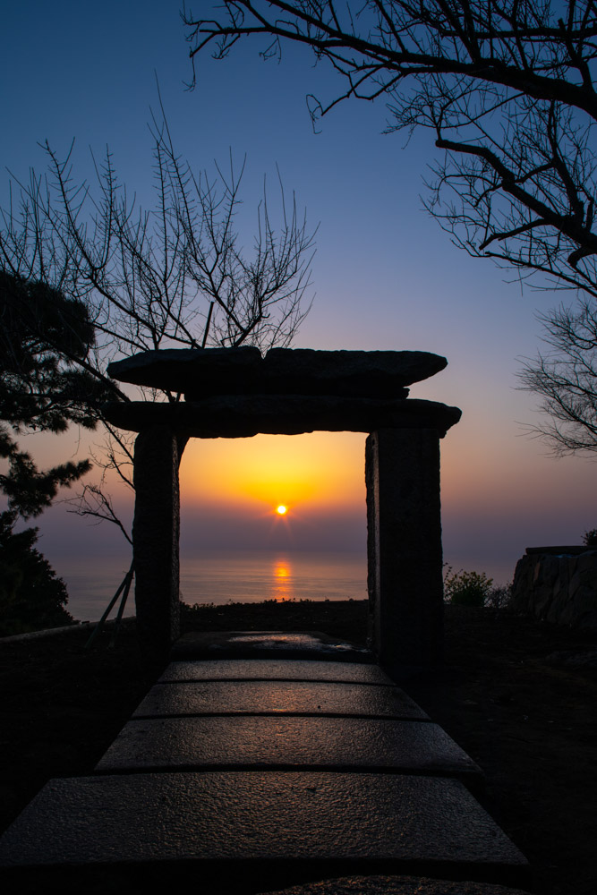 The rising sun seen through the stone torii gate of the Uchōten Teahouse,