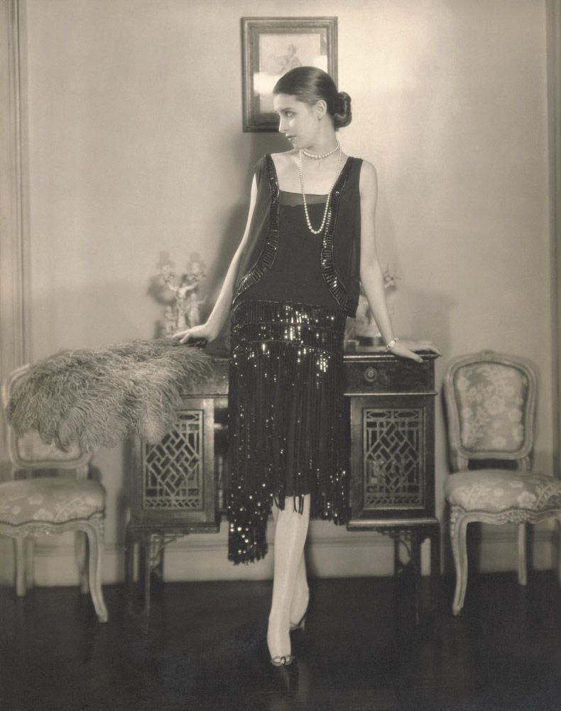 Edward Steichen, Model Marion Morehouse wearing a Chanel black crepe romain bolero dress and skirt with embroidered sequined fringes, black satin shoes by Cammeyer, while standing and holding an ostrich feather fan in the apartment of Cond Nast, from 
