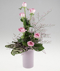 Six lavender roses in cylinder vase.